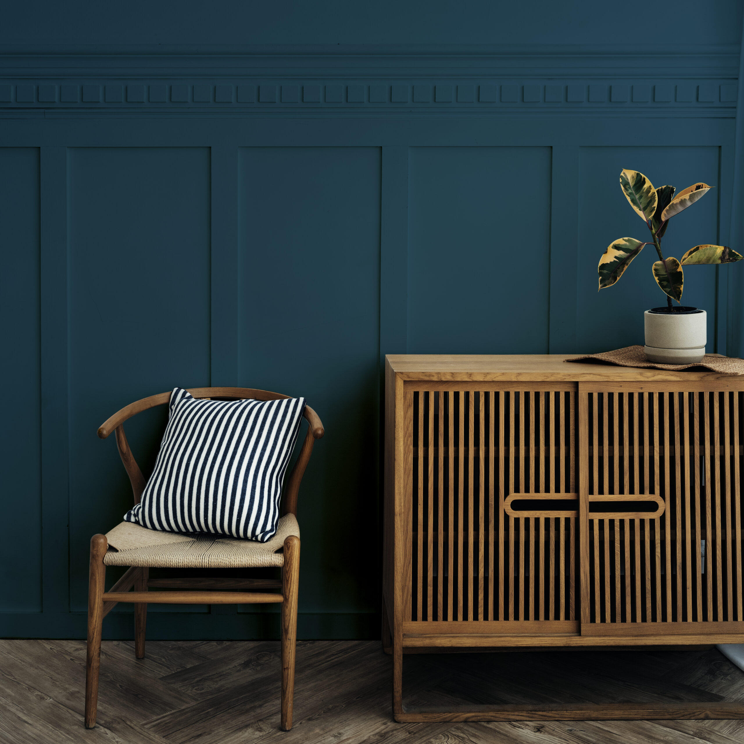 Scandinavian vintage wood cabinet with chair by a dark blue wall